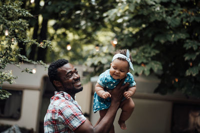 Father carrying daughter on shoulder outdoors