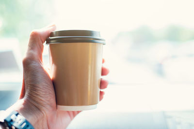 Close-up of hand holding coffee cup