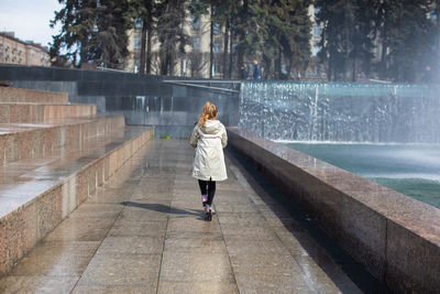 Happy little cute girl having fun in splashes a fountain