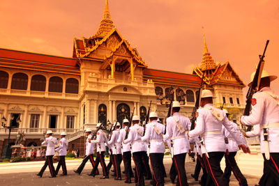 Army soldiers marching by historic building during sunset