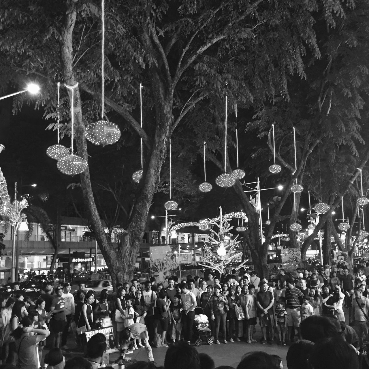 illuminated, large group of people, night, men, lifestyles, crowd, person, tree, lighting equipment, leisure activity, celebration, street light, arts culture and entertainment, event, city, city life, mixed age range, street, enjoyment