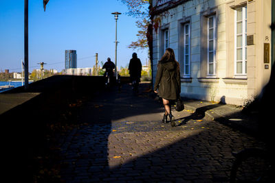 Rear view of people walking on footpath in city
