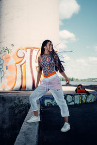 Full length of woman standing against graffiti