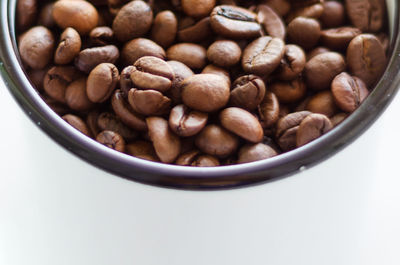 Roasted coffee beans in a mug on a white background