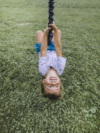 High angle view of boy on swing over grassy field