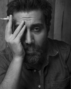Close-up portrait of man smoking cigarette against wall