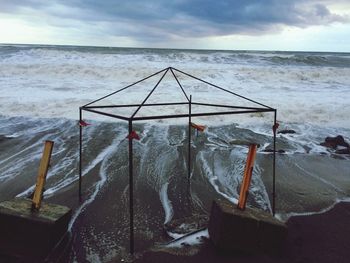 Broken lifeguard hut at beach against dramatic sky