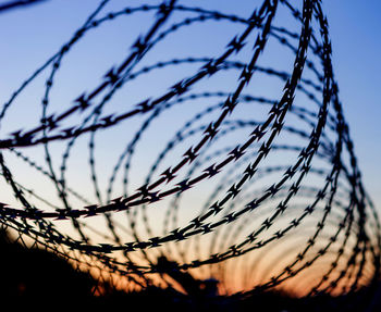 Low angle view of silhouette fence against sky during sunset