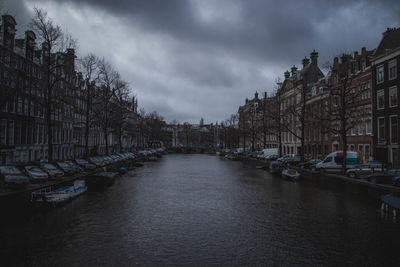 Canal amidst buildings in city against sky