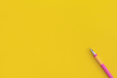 Directly above shot of pencil against yellow background