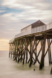 Pier over sea against sky during sunset