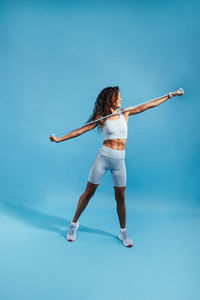 Full length of woman exercising against blue background