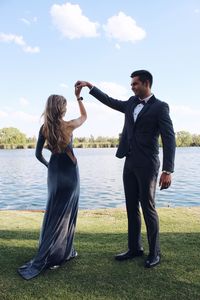 Couple dancing at lakeshore against sky