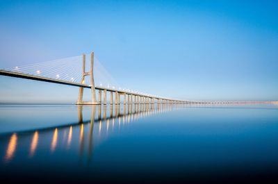Bridge over sea against clear blue sky