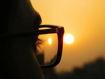 Close-up portrait of hand against orange sky during sunset