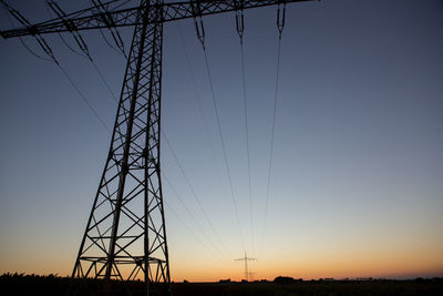 Low angle view of silhouette electricity pylon against sky during sunset