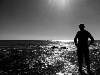 Silhouette man looking at sea against sky