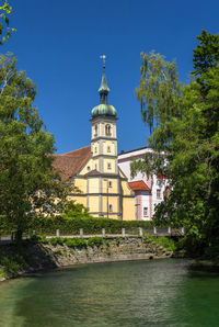 View of river by building against blue sky
