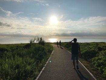 Rear view of man walking on road against sky