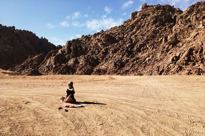 Woman standing on rock in desert against sky