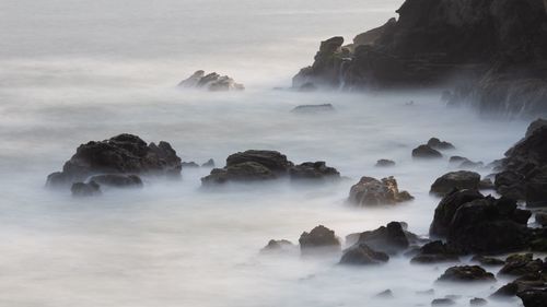 Scenic view of rocks in sea against sky