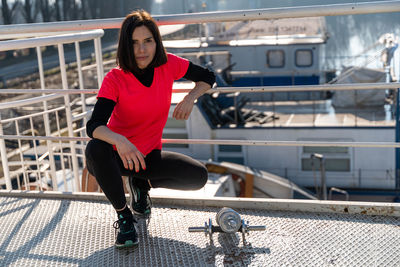 Portrait of woman crouching by railing