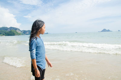 Teenage girl standing on shore against sea at beach