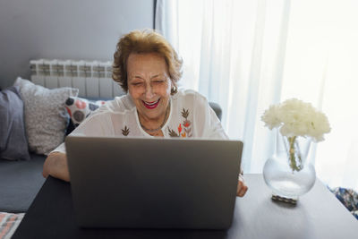 Smiling senior woman using laptop at home