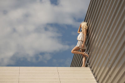 Low angle view of woman standing on steps against sky