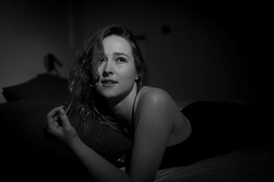 Portrait of young woman sitting on bed at home