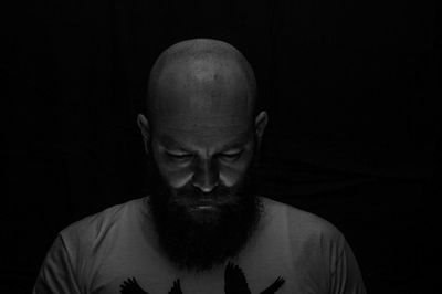 Close-up of bearded man against black background