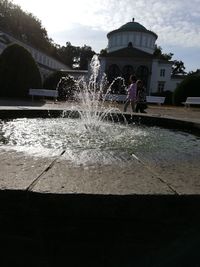 People standing by fountain in front of building