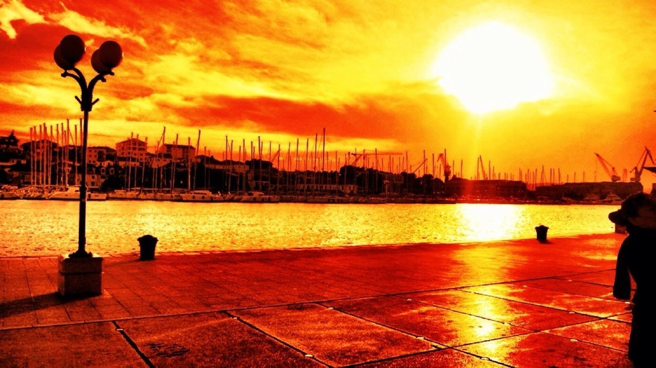 sunset, water, orange color, sun, sky, silhouette, transportation, nautical vessel, reflection, sunlight, river, sea, mode of transport, street light, cloud - sky, sunbeam, scenics, beauty in nature, nature