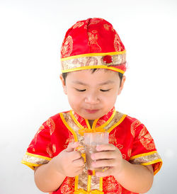 Close-up of a boy holding drink against white background