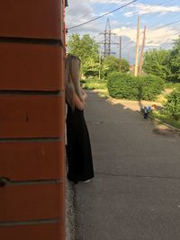 Rear view of woman on road against plants