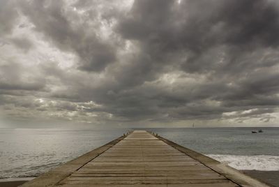 Pier over sea against cloudy sky