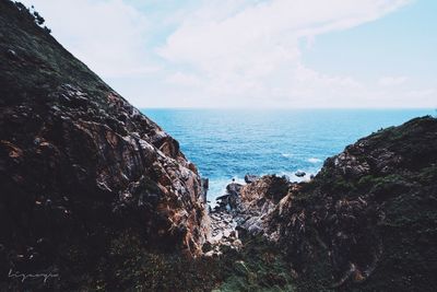 Scenic view of sea by cliff against sky