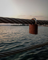 Close-up of padlocks on railing against sea