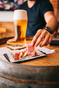 Midsection of woman holding beer glass on table