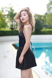 Portrait of young woman standing against wall