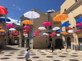 People walking on multi colored umbrellas against buildings