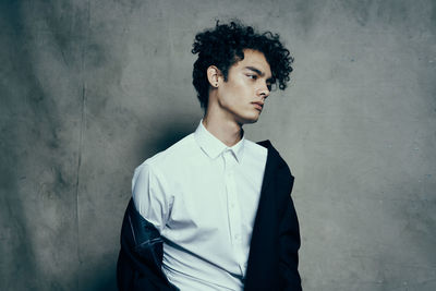 Young man looking away against wall