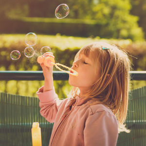 Close-up of girl blowing bubbles at park