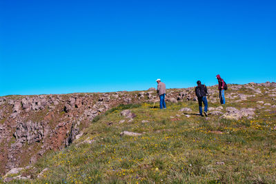 People on landscape against clear blue sky