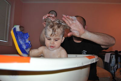 Father bathing son in bathtub at bathroom