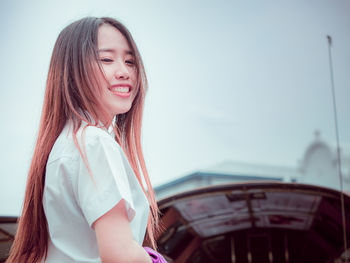 Portrait of a smiling young woman in boat against sky