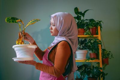 Side view of woman standing by potted plant