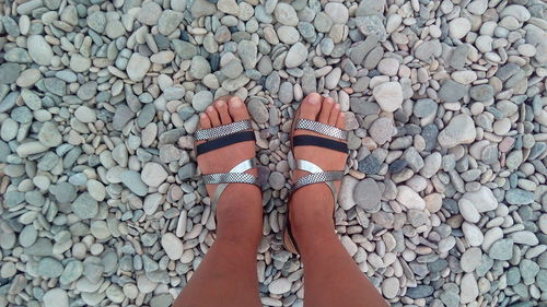 Low section of woman standing on pebbles