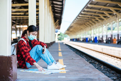 Woman sitting on railroad station platform