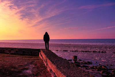 Man looking at sea against sky during sunset